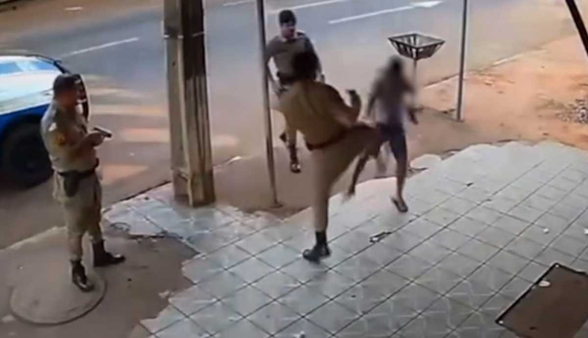 Câmera flagra PM dando chutes em jovem na frente de distribuidora que ele trabalha; Vídeo